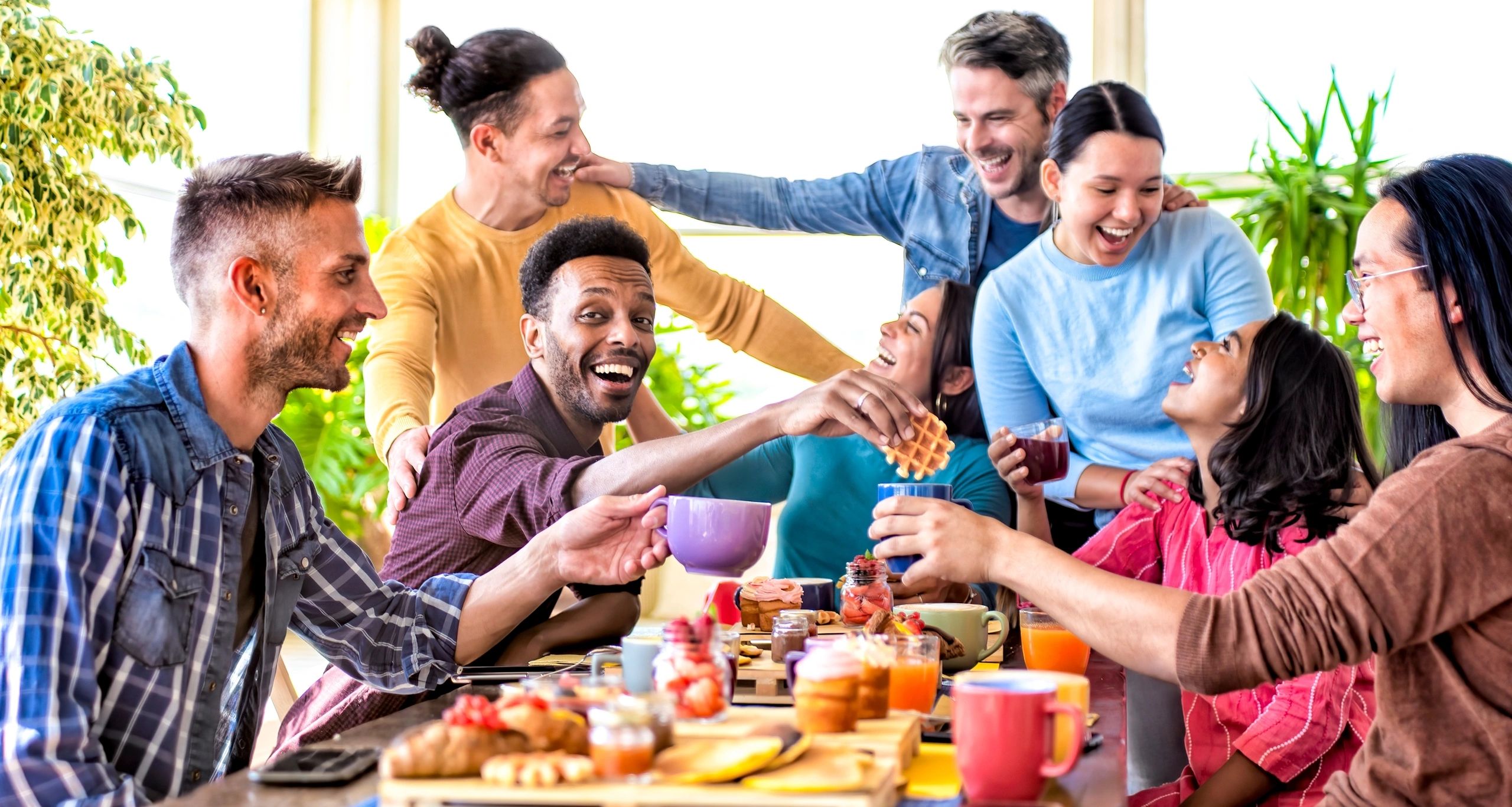 Group of friends enjoying a lively breakfast gathering with laughter and food.
