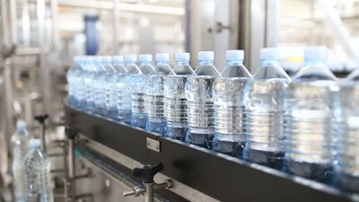 Plastic water bottles lined up on a production conveyor belt.