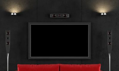 Modern home theater setup with a red sofa and black walls.