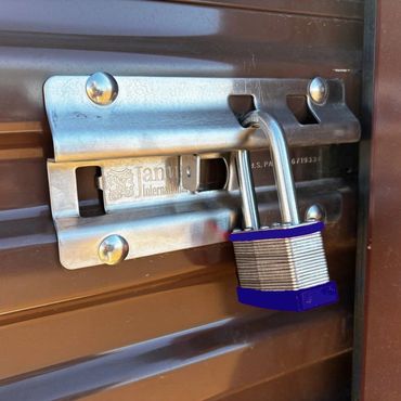 Close-up of a silver padlock securing a brown metal latch on a door.