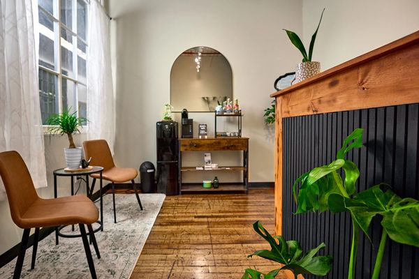 Bright reception area with natural light, warm wood accents, plants, and comfortable seating.
