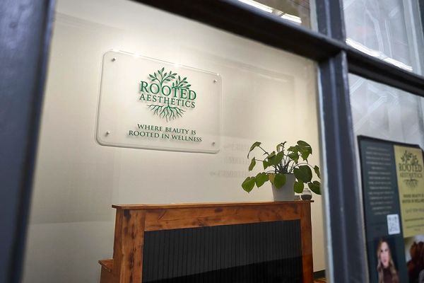 Reception desk at Rooted Aesthetics with welcoming signage and calming botanical décor.