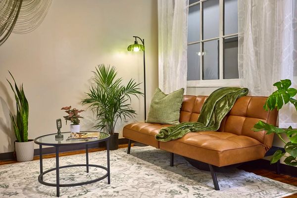 Comfortable client lounge with leather sofa, plants, soft lighting, and relaxing atmosphere.