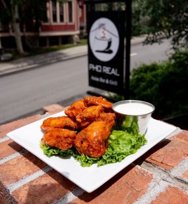 Spicy buffalo chicken wings with ranch dip on a white plate.