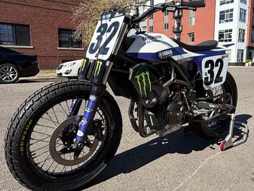 Yamaha racing dirt bike with number 32 parked on a city street.