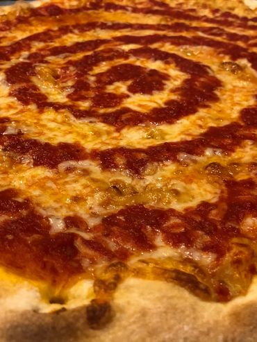 Close-up of a cheese pizza with spiral tomato sauce.