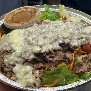 A leafy salad topped with ground beef and creamy dressing.