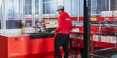 Worker operating an AutoStore robotic storage system in a warehouse.