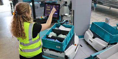 Warehouse worker using touchscreen to scan items on an automated robot.