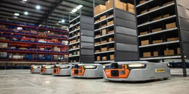 Automated robots transporting shelves with packages in a warehouse.