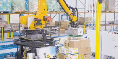 Robotic arm automating palletizing boxes in a warehouse.