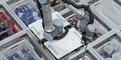 Robotic arms sorting groceries in an Ocado automated warehouse.