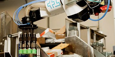 Robotic arm sorting packages on a conveyor belt in a warehouse.