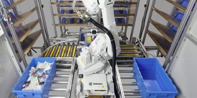 A robotic arm sorting items into blue bins in an automated system.