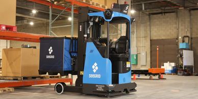 A blue Seegrid automated forklift in a warehouse environment.