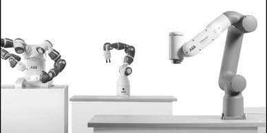 Three robotic arms from ABB displayed on pedestals against a white background.