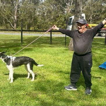 Man excitedly holding a dog on a leash outdoors.