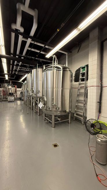 Shiny stainless steel brewing tanks in a clean industrial space.
