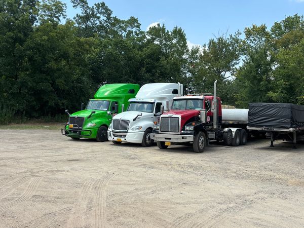 Three trucks parked side by side on a dirt lot.