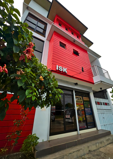 Modern red and white building with ISK sign and greenery.