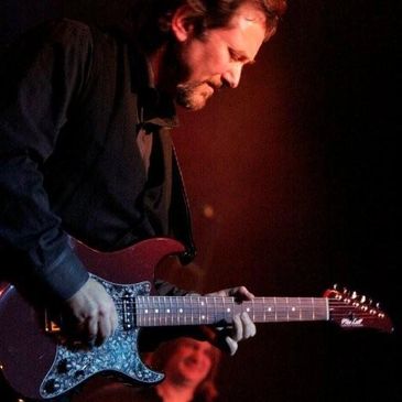 Musician passionately playing an electric guitar on stage.