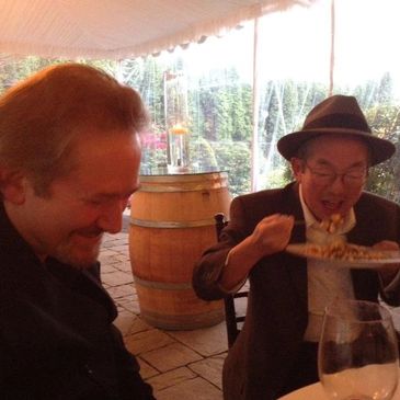 Two men enjoying a meal and laughter at an outdoor restaurant.