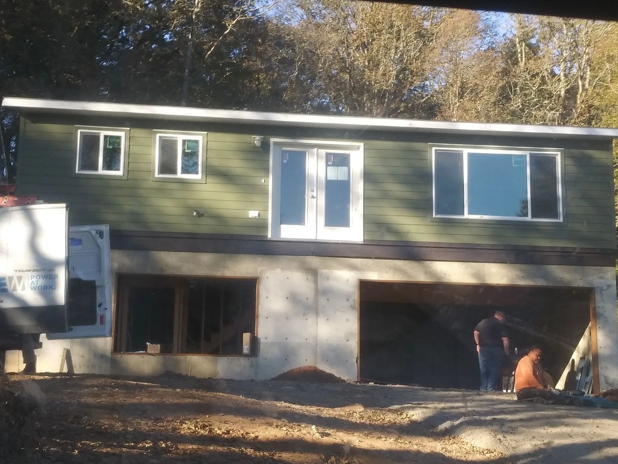 A house under construction with workers outside the garage area.