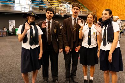 Group of students in school uniforms waving.