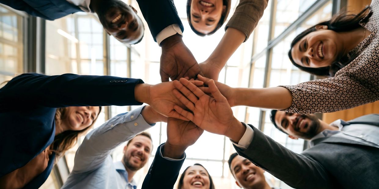 Group of coworkers stacking hands in unity.
