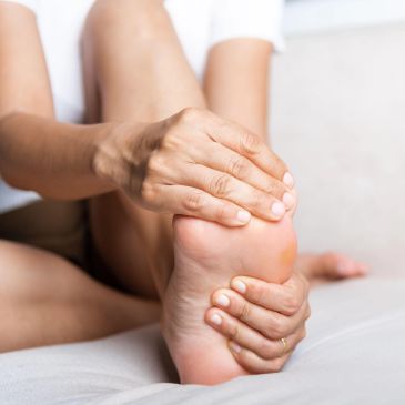 Person holding their painful foot.