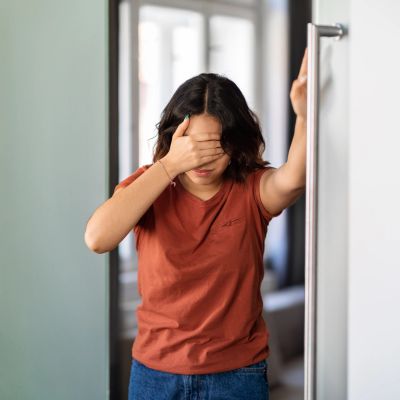 A woman stressed, covering her face with her hand.