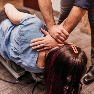 Chiropractor adjusting woman's back on table.