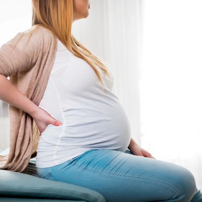 Pregnant woman holding her back in discomfort.