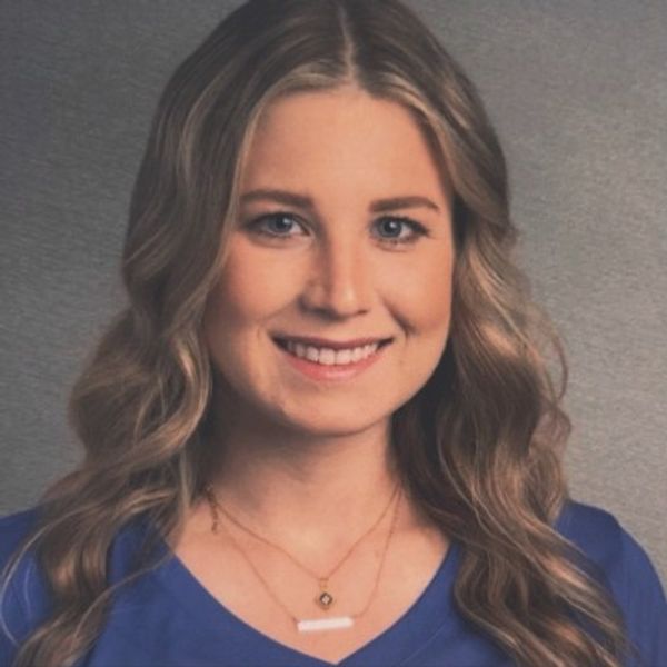 Smiling young woman with wavy blonde hair and blue top.