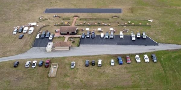 Aerial view of a parking lot with cars and surrounding grassland.