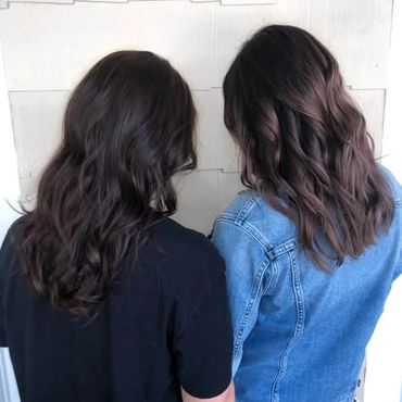 two girls facing a wall showcasing the new brown color that they just had added to their hair
