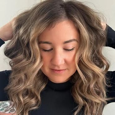 a girl with her hands running through her hair showing off the fresh cut and color