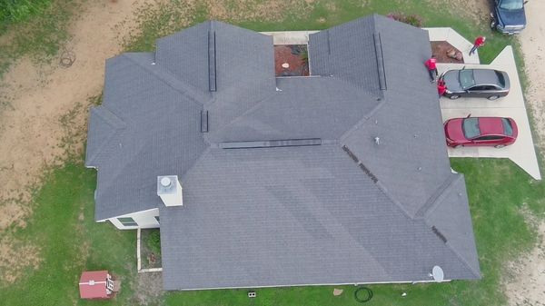 Aerial view of a house with a gray roof and driveway with cars. roof repair