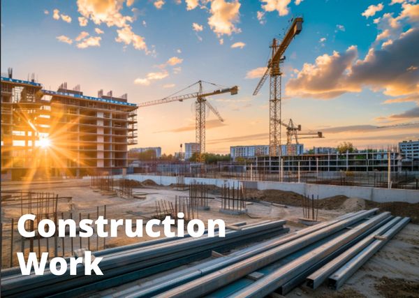 Sunset over an active construction site with cranes and building materials.