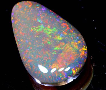 A polished opal gemstone displaying vibrant multicolor flashes.