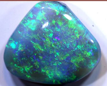 Close-up of a polished opal gemstone with vibrant blue and green colors.