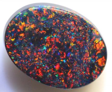 Oval opal gemstone with vibrant fiery colors and iridescent flashes.
