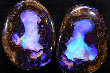 Two polished opal stones with vibrant blue and purple hues.