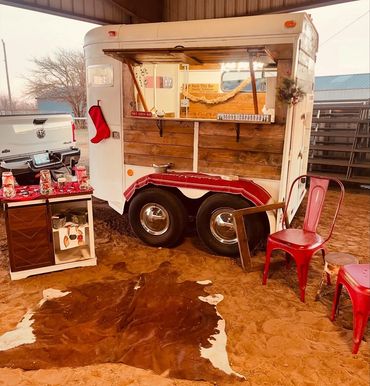 Festive hot cocoa bar setup in a rustic outdoor setting with red chairs and decorations.
