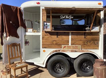 Mobile bar setup in a trailer with rustic wood paneling and western decor.