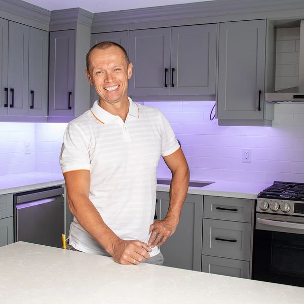 new age interiors owner standing and smiling in front of the kitchen