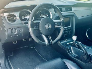 Interior of a sporty car with a manual transmission and Shelby steering wheel.
