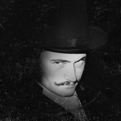 Man with a mustache and hat in a moody black-and-white photo.