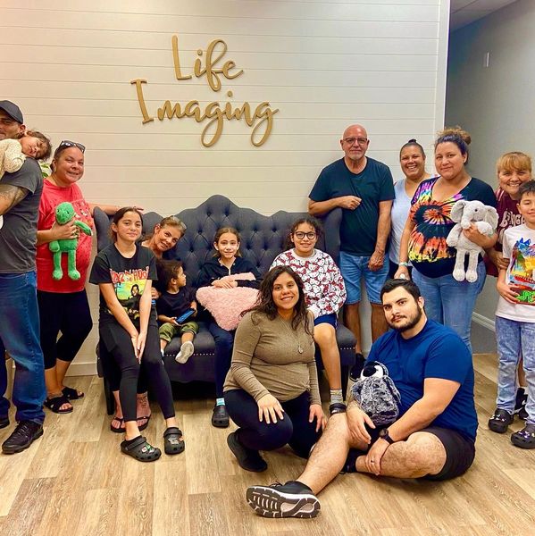 Group photo of people posing indoors under 'Life Imaging' sign.