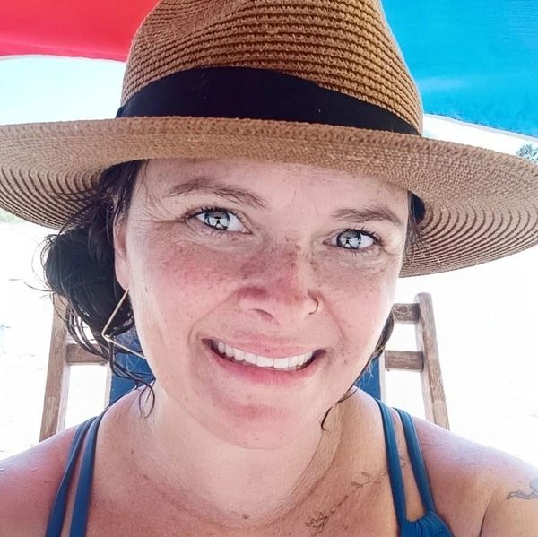 Smiling woman wearing a straw hat and blue swimsuit.
